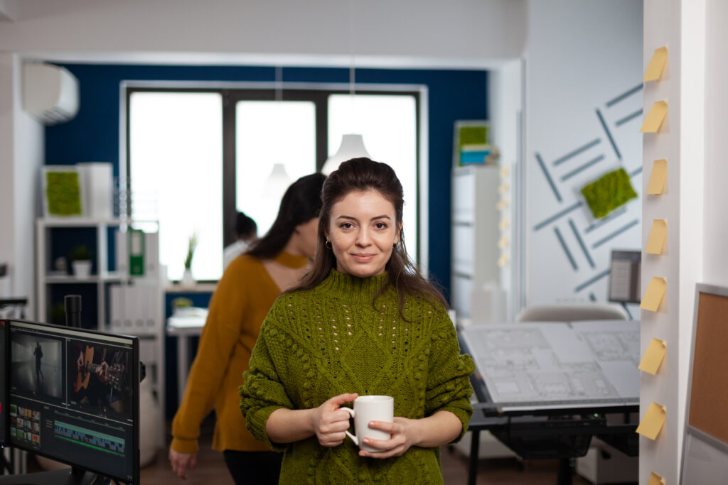 Portrait of designer artist smiling at camera holding cup of coffee