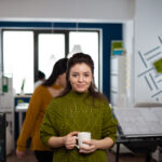 Portrait of designer artist smiling at camera holding cup of coffee